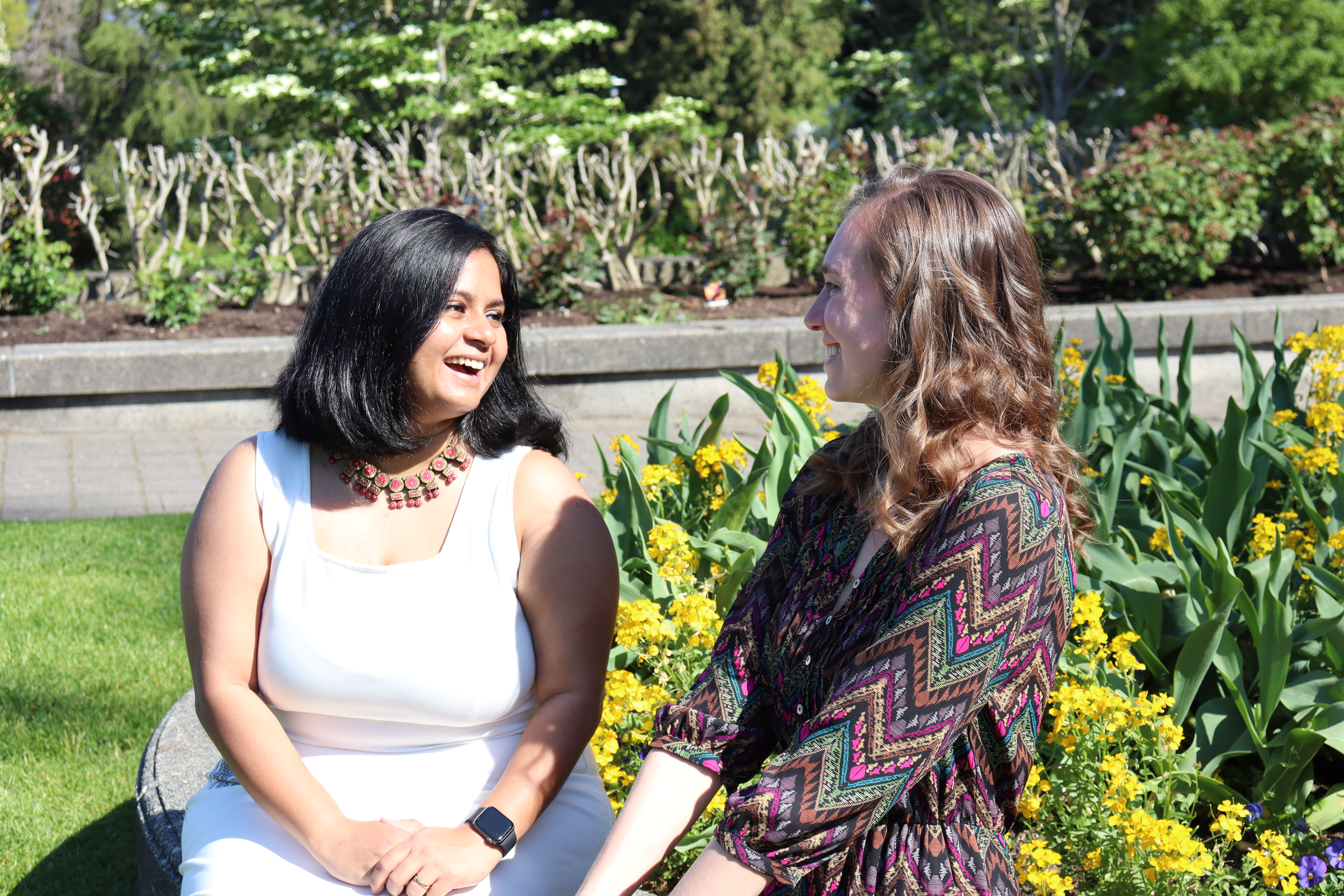 Meghna and Madison laughing with each other in sunny garden