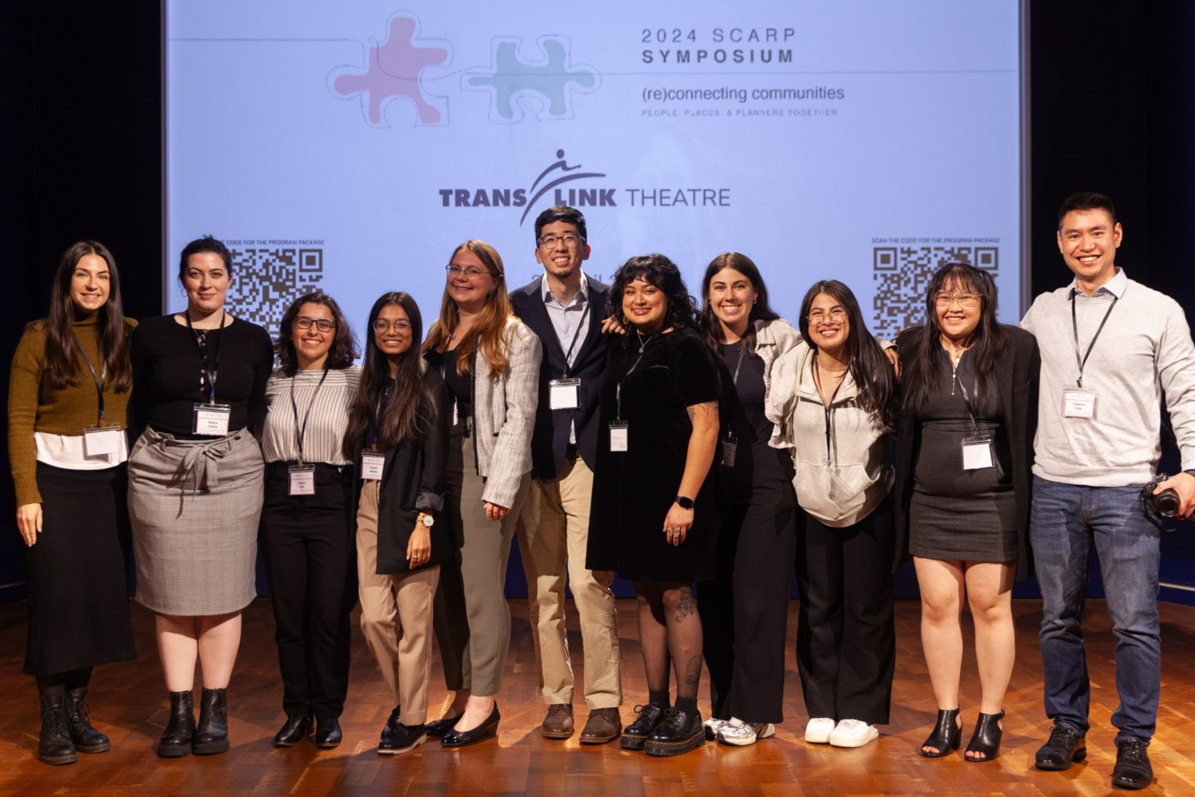 Students arm-in-arm on stage, in front of "SCARP Symposium" logo