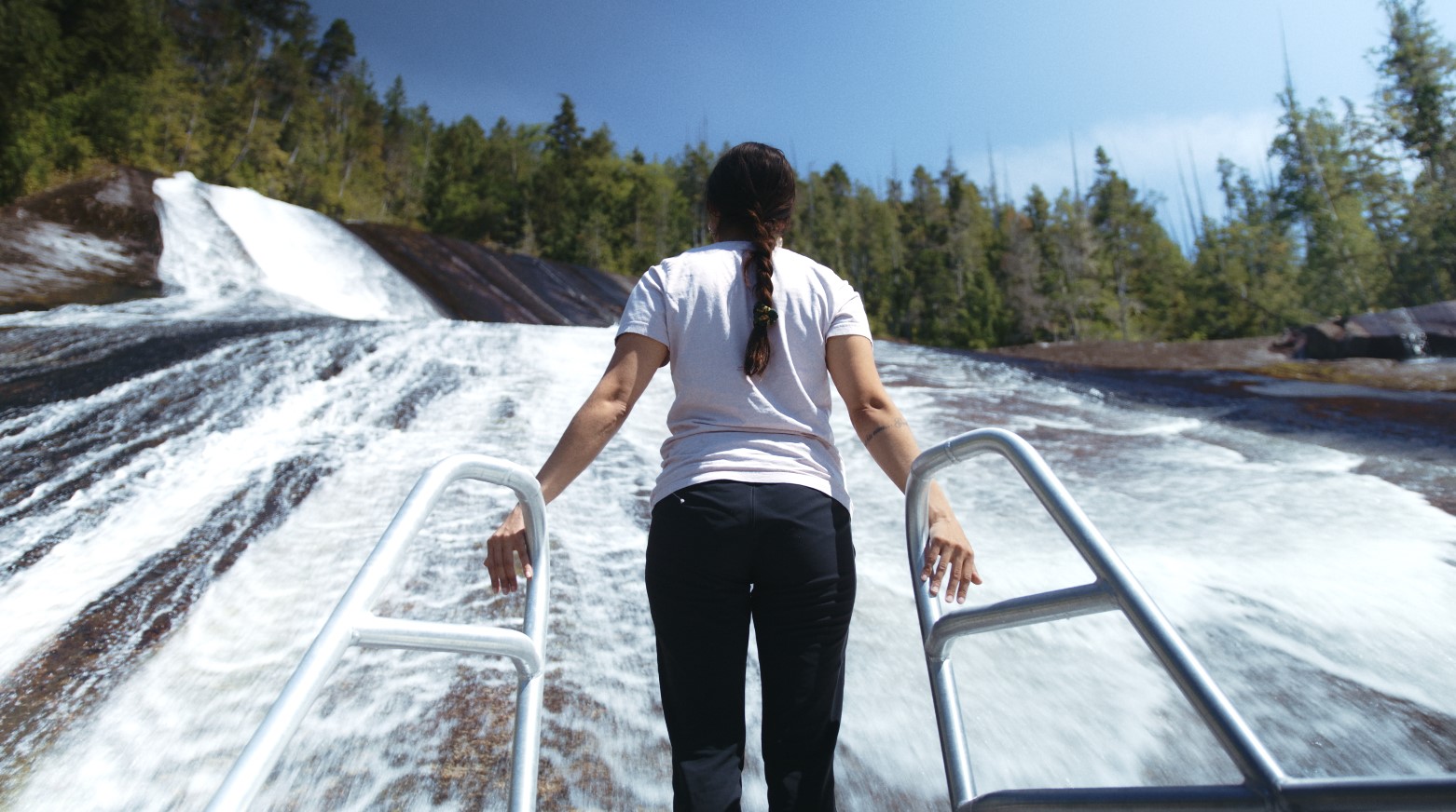 Woman hanging onto bars in front of waterfall