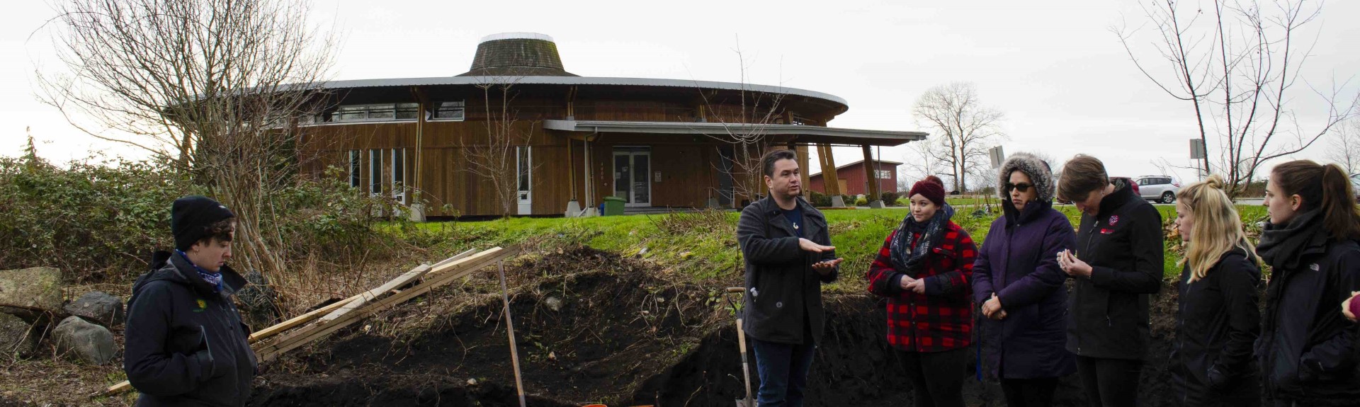 An Indigenous man teaching students outside a cylindrical building