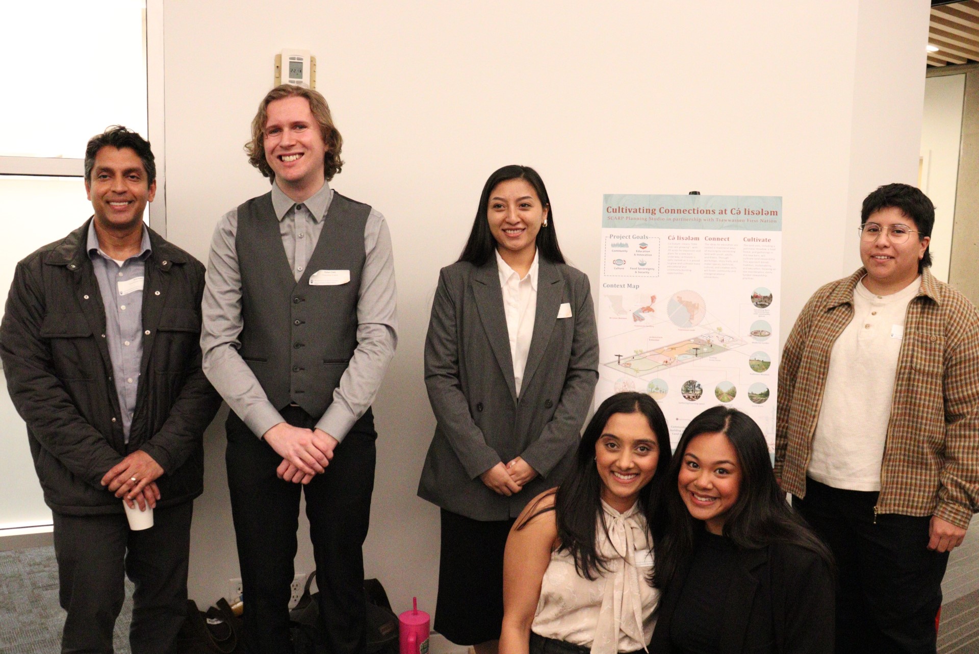 Students and partners posing around a project poster