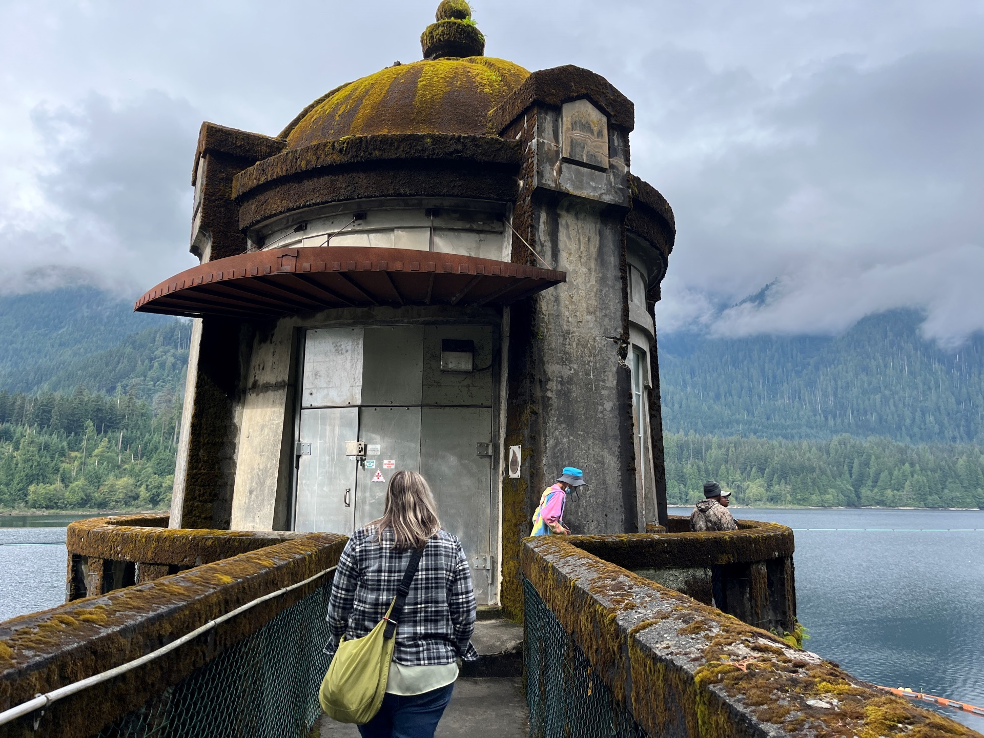 Faculty and students traverse a mysterious moss-roofed shed among a seaside mountain