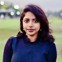 Woman in green field with building
