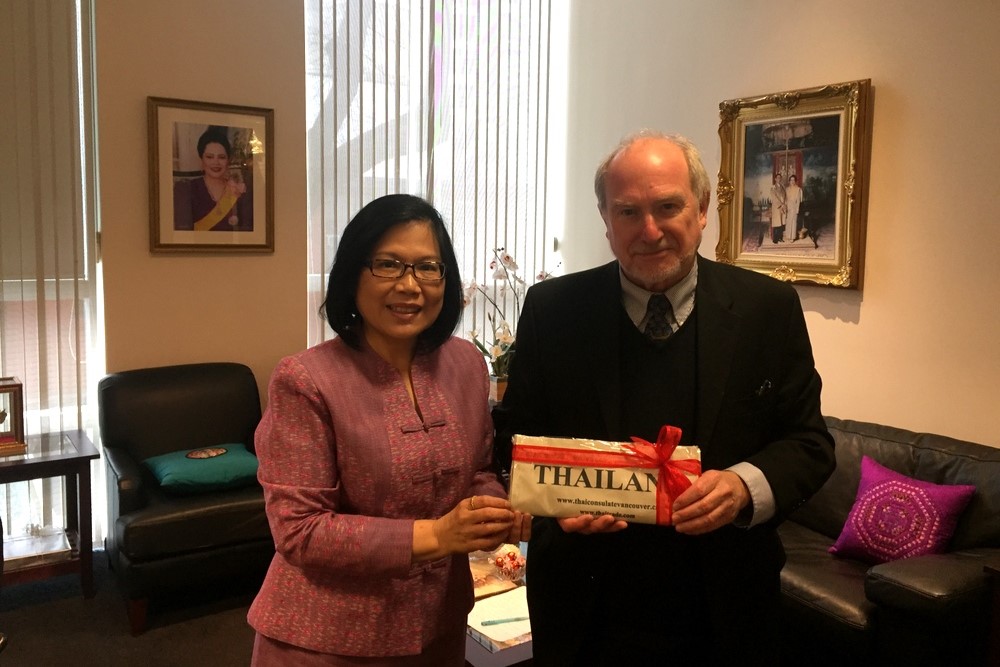 Man and woman ceremoniously holding a bow-wrapped paper labeled "Thailand"