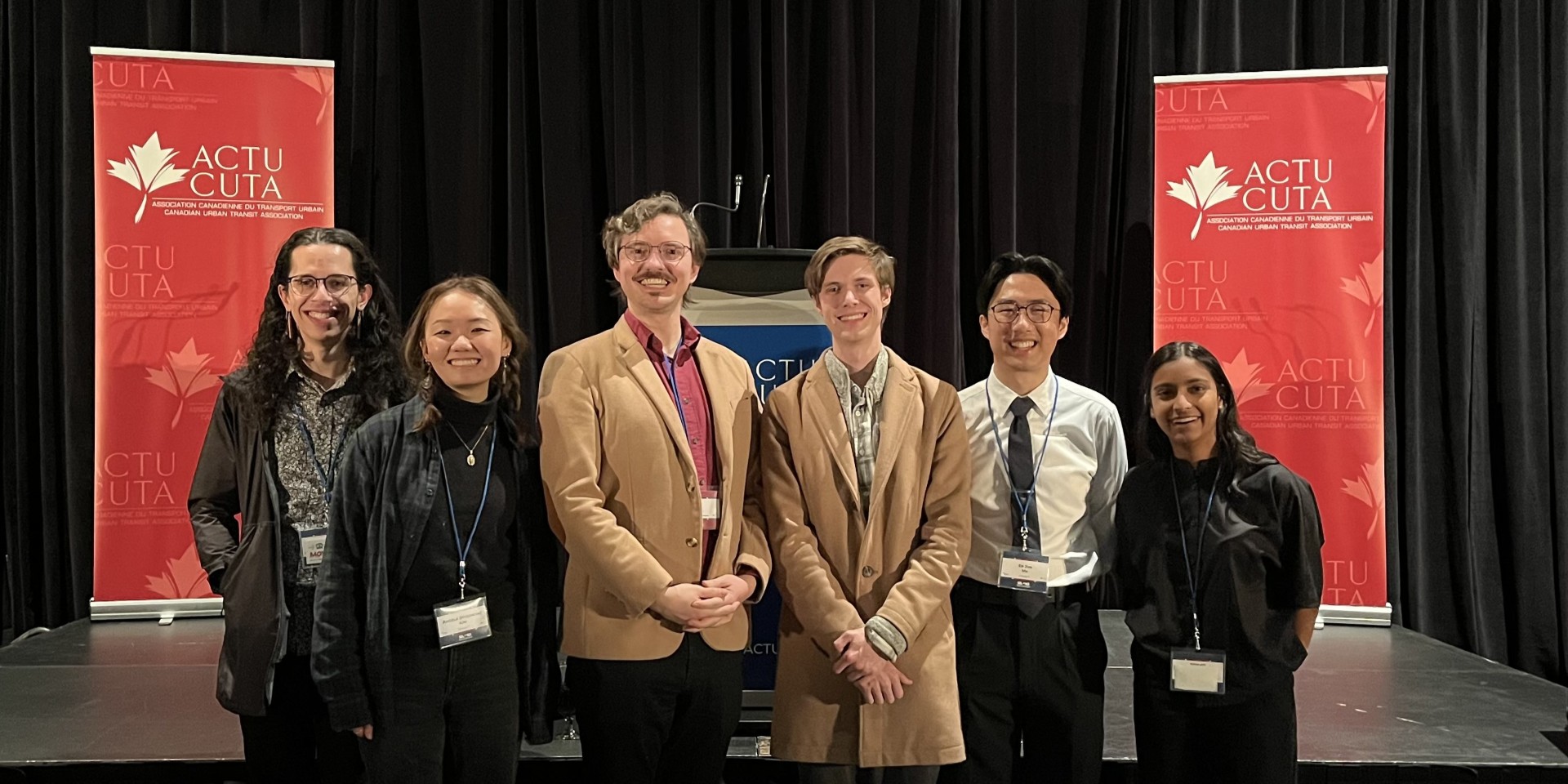 Six youth posing in front of "ACTU" event banners