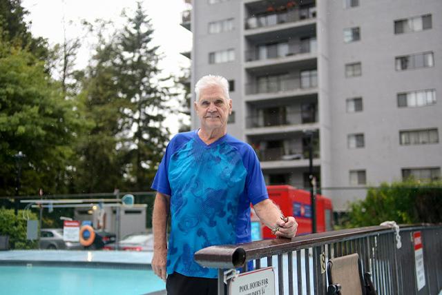 A man standing by a railing in front of a pool.