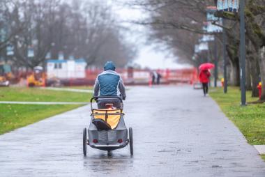 Cyclist in carriage-carrying bicycle, on a rainy day at UBC
