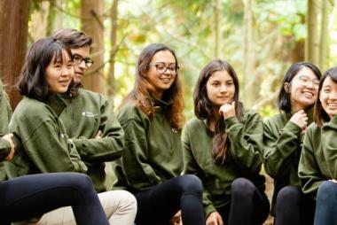 Severlal students in UBC Sustainability shirts sitting in a forest clearing