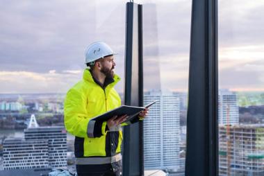 Engineer holding book looking at city from skyscraper