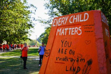 Small monument painted orange with messages that every child matters and that we are on Musqueam land
