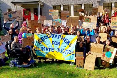 Youth holding up "Geographers for Climate Justice" sign