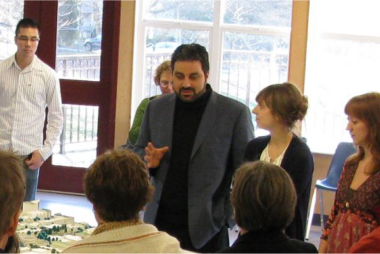 A man in a blazer discussing a town model with students
