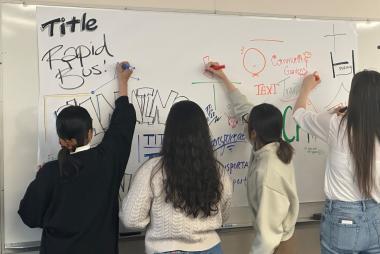Several students writing planning-related terms on a whiteboard