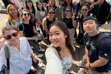 A group of students and a young instructor making a selfie at a seaside market