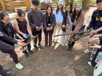 Students in a circle presenting twigs to one another