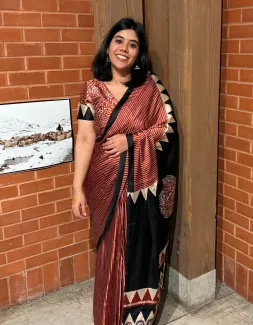 Woman in red dress leaning against a post by a brick wall