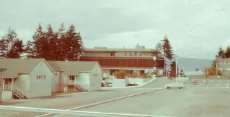 An old photograph of UBC's campus, showing far more road infrastructure and small houses beside admin buildings