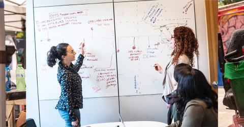Two people consulting a whiteboard in collaboration