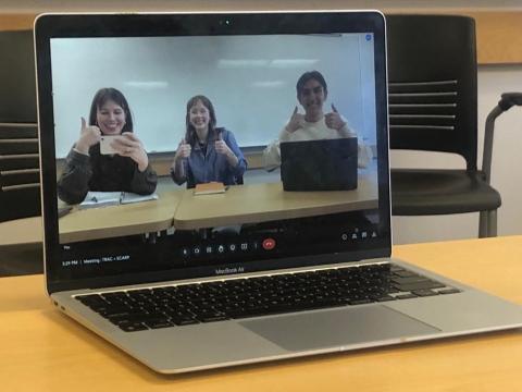 Three students, in a picture on a laptop, smiling with thumbs-up