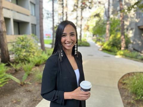 A woman in a UBC pathway holding a UBC-bought hot drink