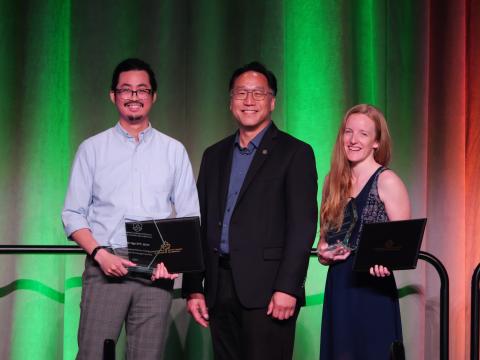 Young people holding awards with older man in between them