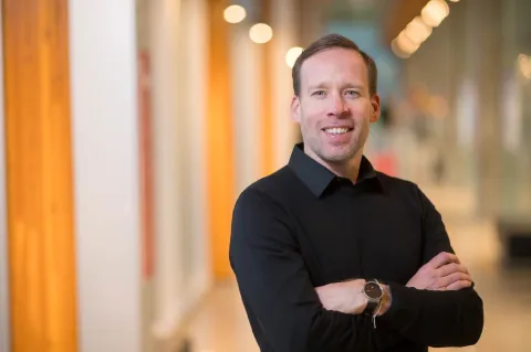 Man in button-up shirt, smiling with arms folded