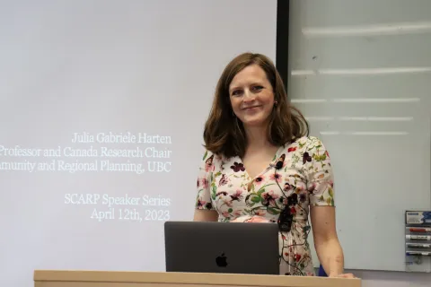 Woman presenting at lectern in front of big screen