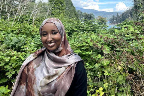 Woman posing in forest with mountains in the background