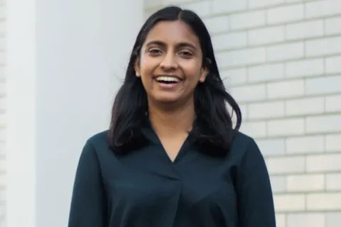 Woman in black button-up top in front of white brick wall
