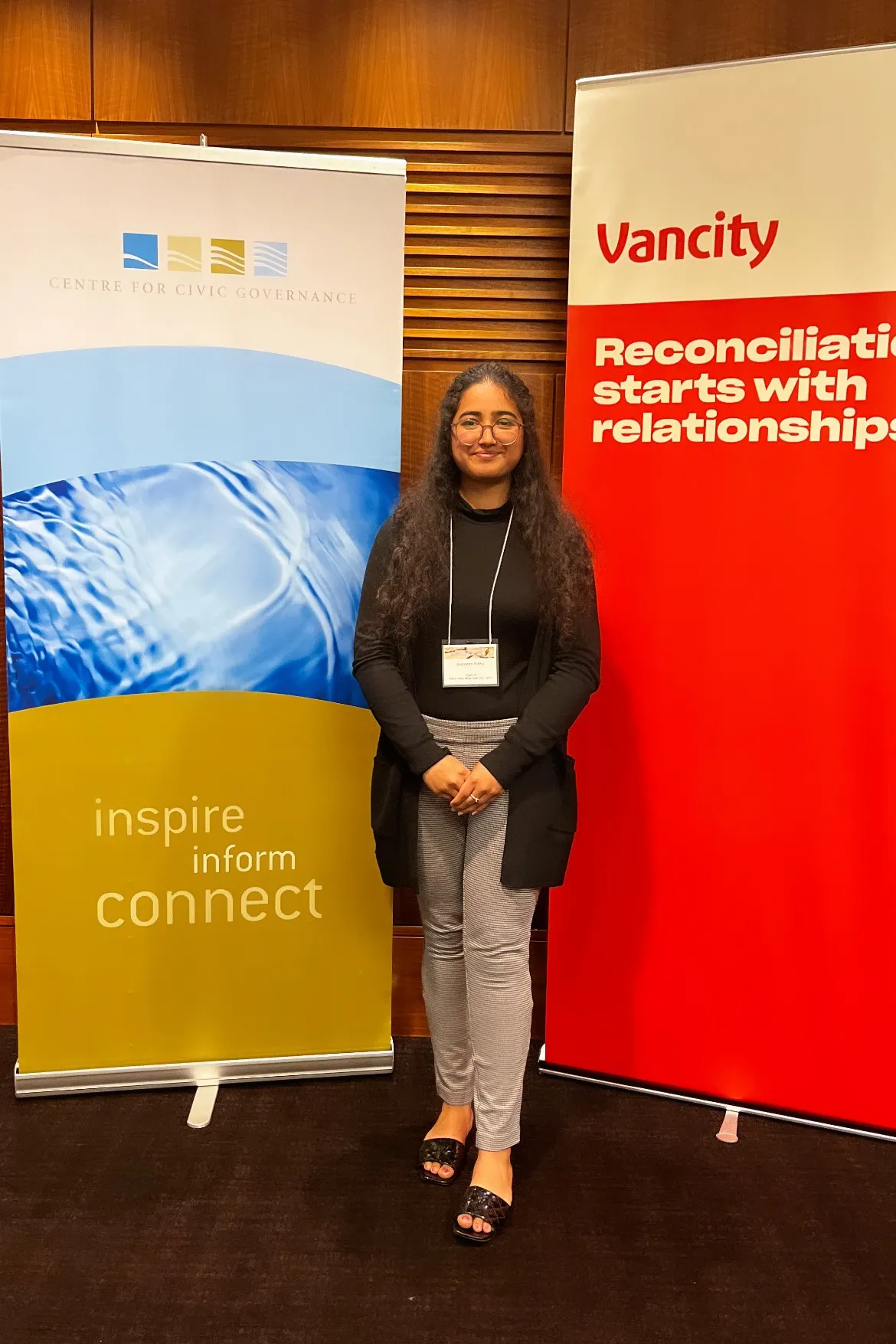 A woman between a Centre for Civic Governance banner and a VanCity banner