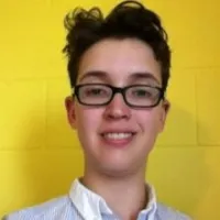 Jen Roberton, smiling before yellow cement wall