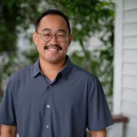 Man in button-up casual shirt outside house