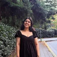 Woman in black dress on cobblestone sidewalk by heavy foliage
